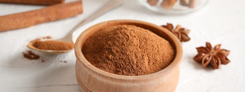 Cinnamon sticks, anise and spoon on white background, space for text